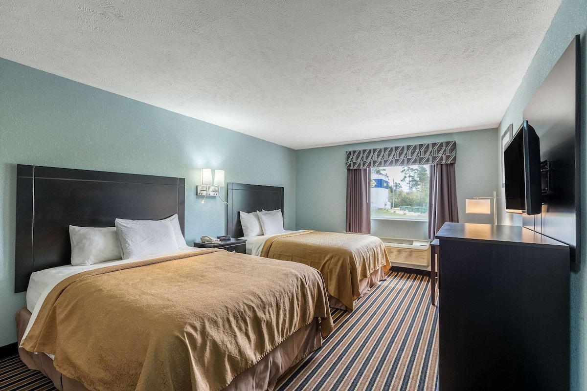 Una habitación de hotel con dos camas, un televisor y una ventana con cortinas.