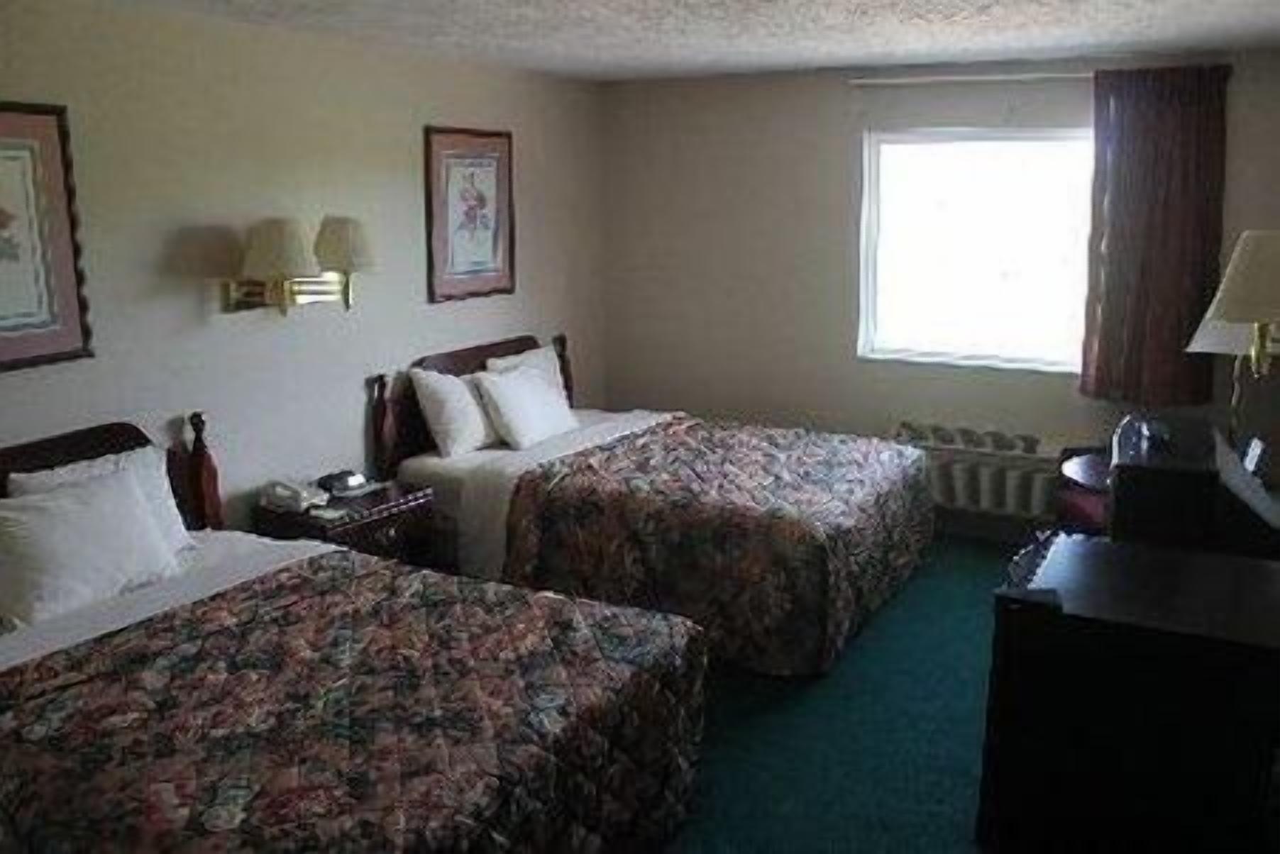 Une chambre d’hôtel avec deux lits, un bureau, une lampe et une fenêtre.