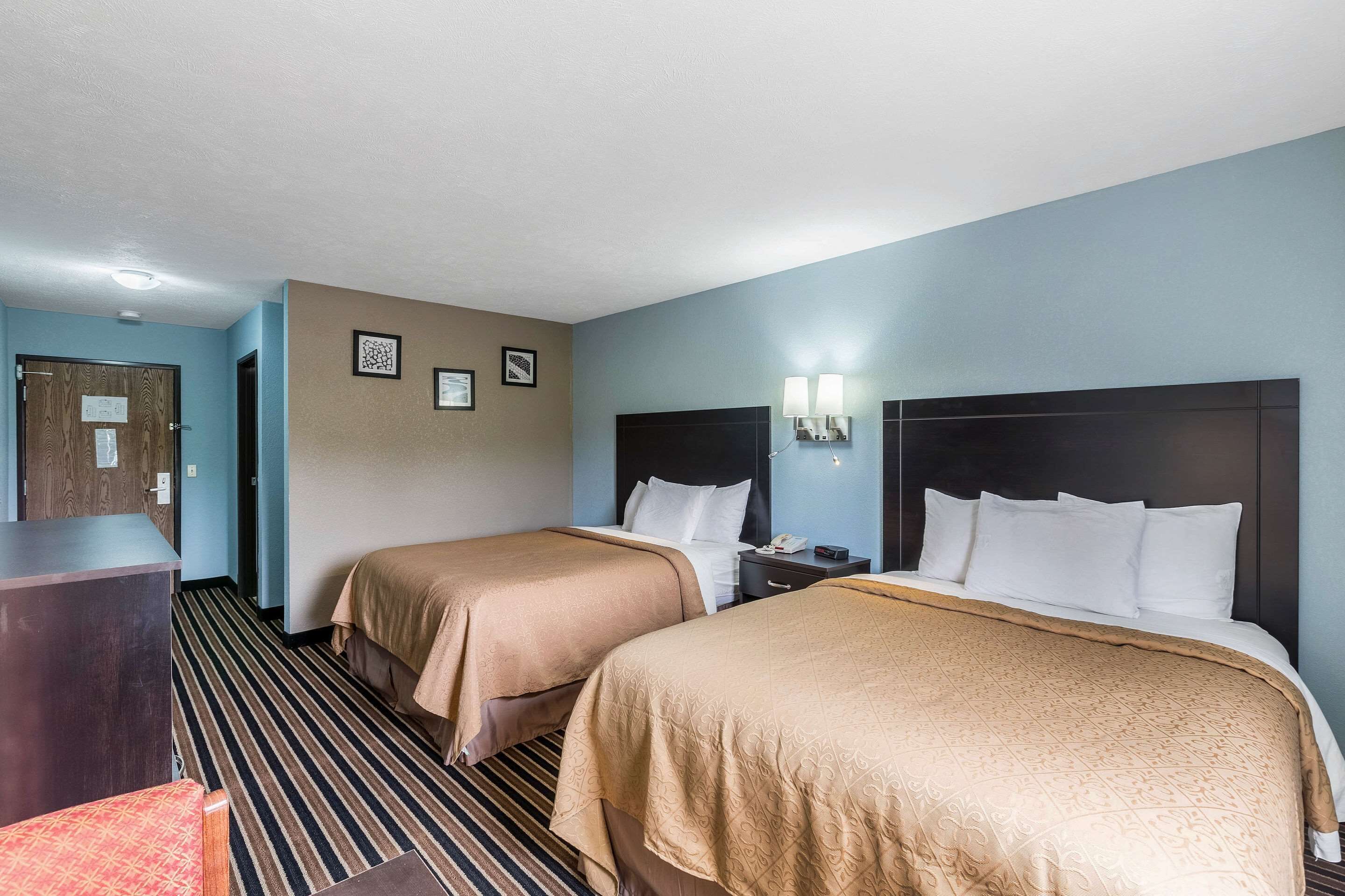 Habitació d'hotel amb dos llits, una taula de treball i una cadira.
