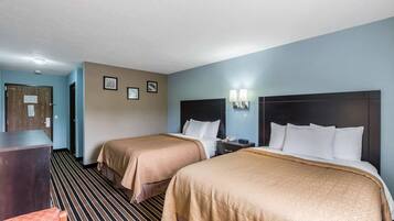 Habitació d'hotel amb dos llits, una taula de treball i una cadira.