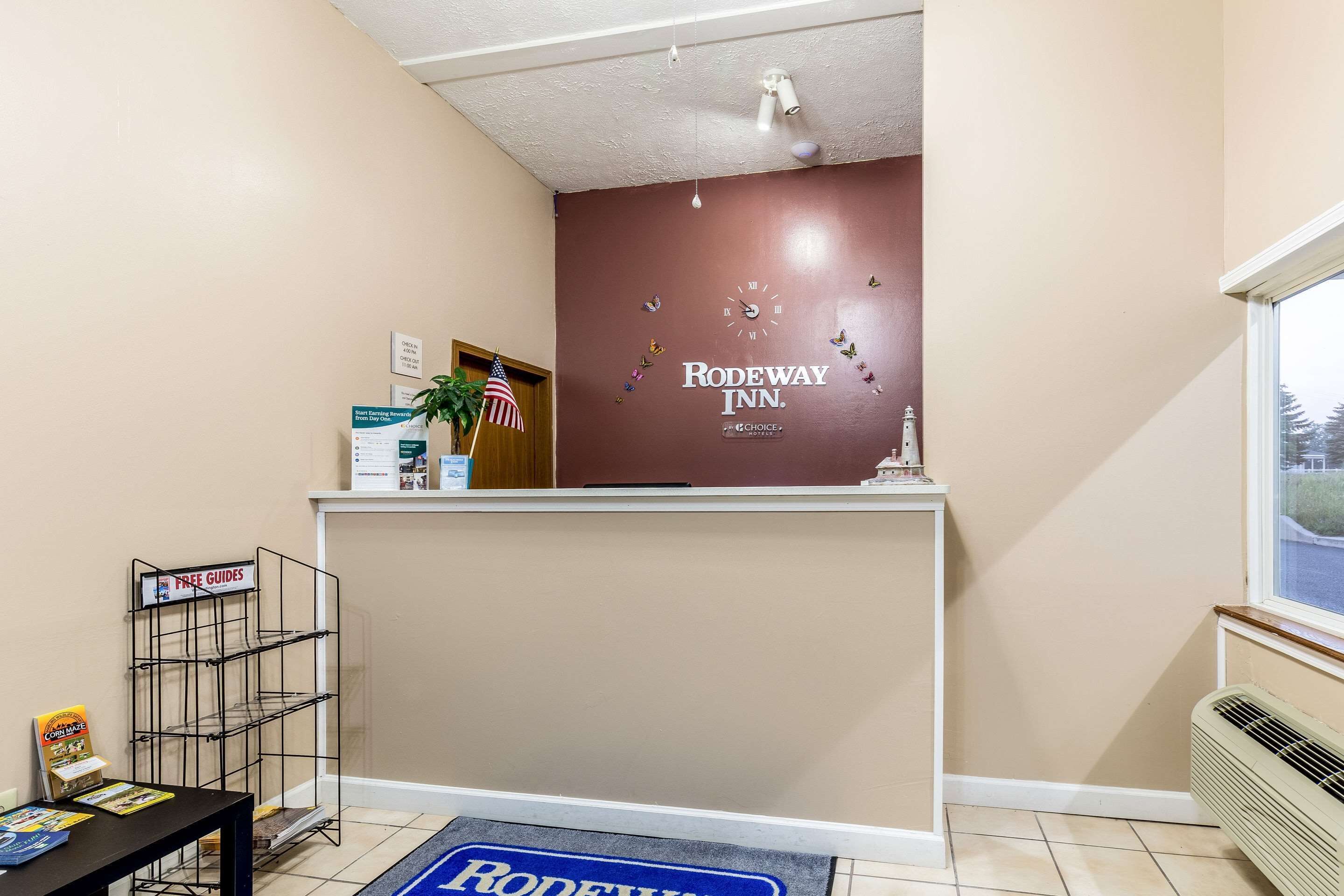 A reception area with a brown wall, a clock, and a sign reading "Rodeway Inn."