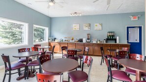 Un restaurante con varias mesas y sillas, una zona de cocina y un letrero de salida.