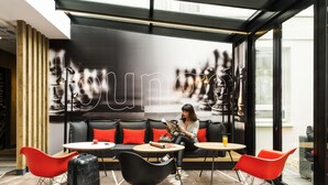 Ein stilvoller Lounge-Bereich mit einer Couch, Schaukelstühlen und einem Tisch mit einem Getränk.