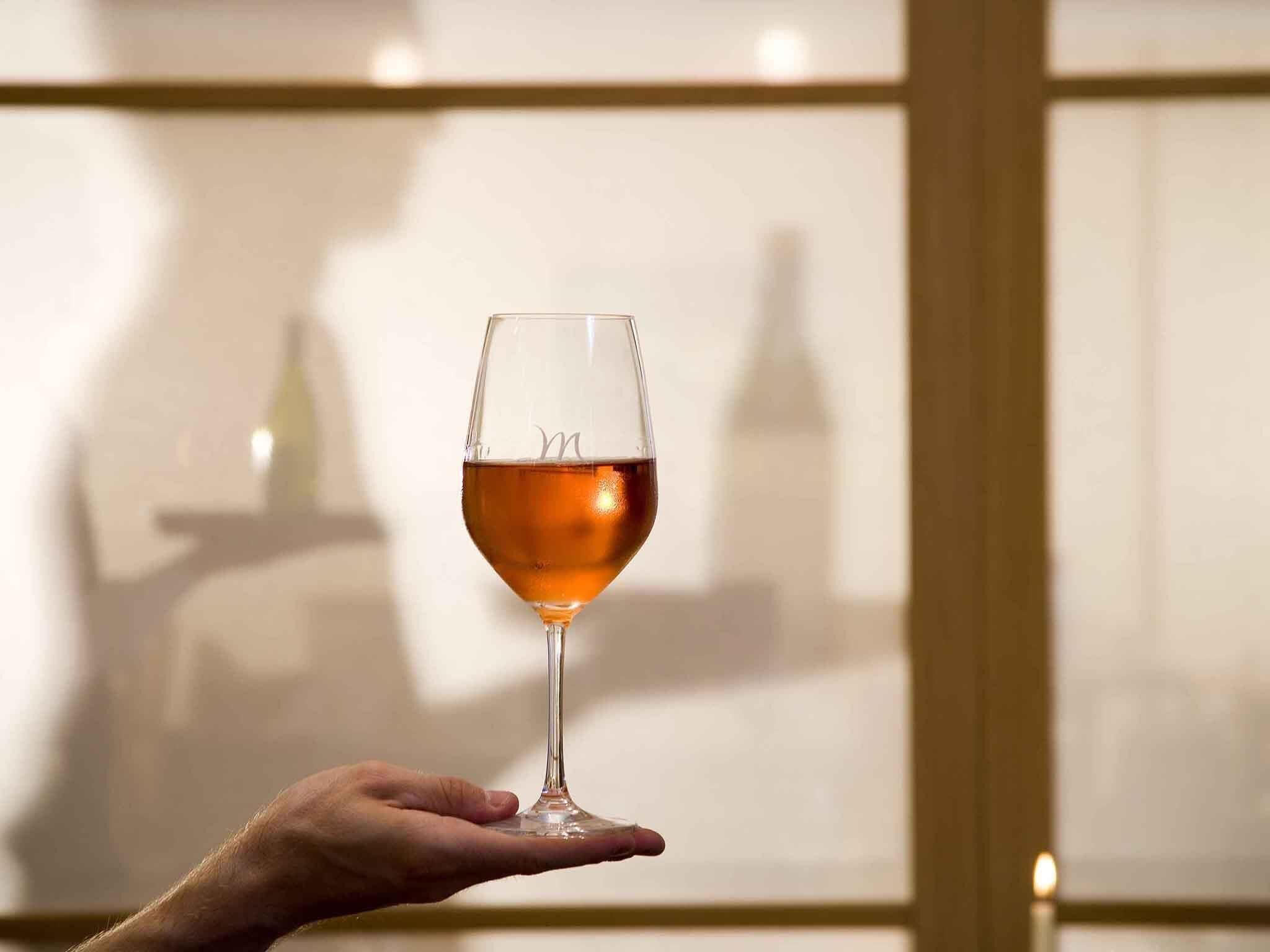 A hand holding a wine glass with a reflection of a building in the background.