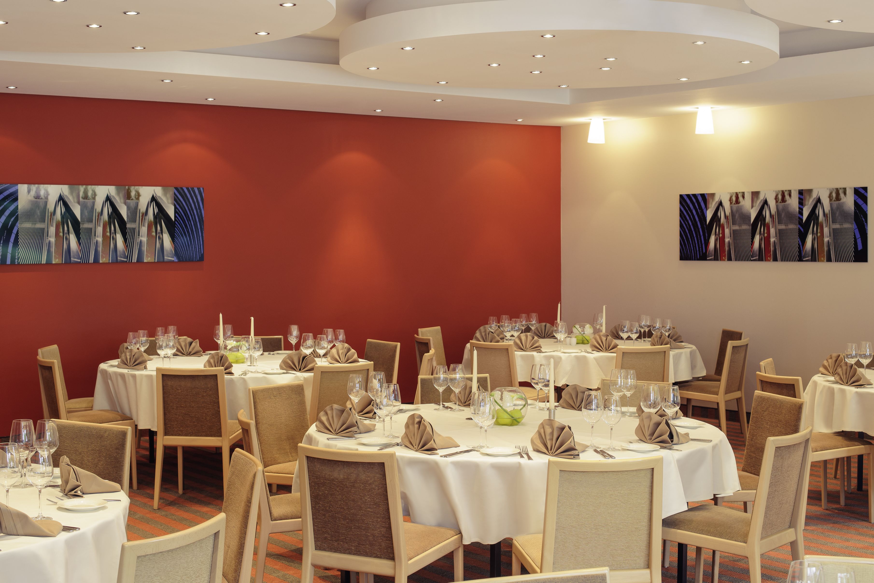 A dining area with round tables, chairs, and artwork on the walls.