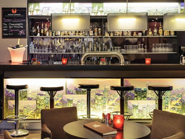 A bar area with a cityscape view, bar stools, and a variety of bottles and glasses. - Mercure Hotel Frankfurt Eschborn Ost (Eschborn)