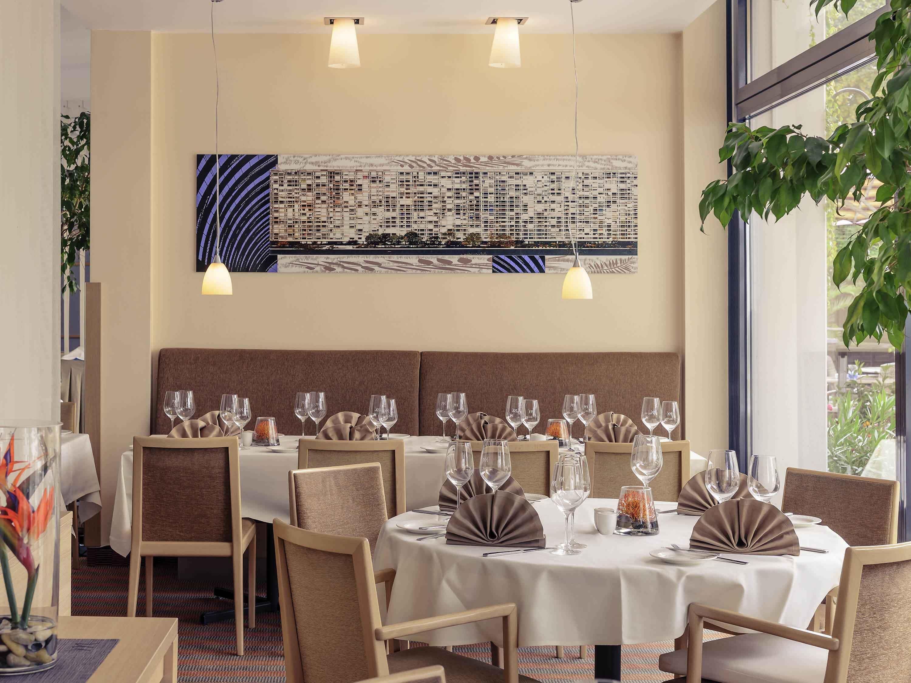 Un restaurante con mesas redondas, sillas y lámparas colgantes.