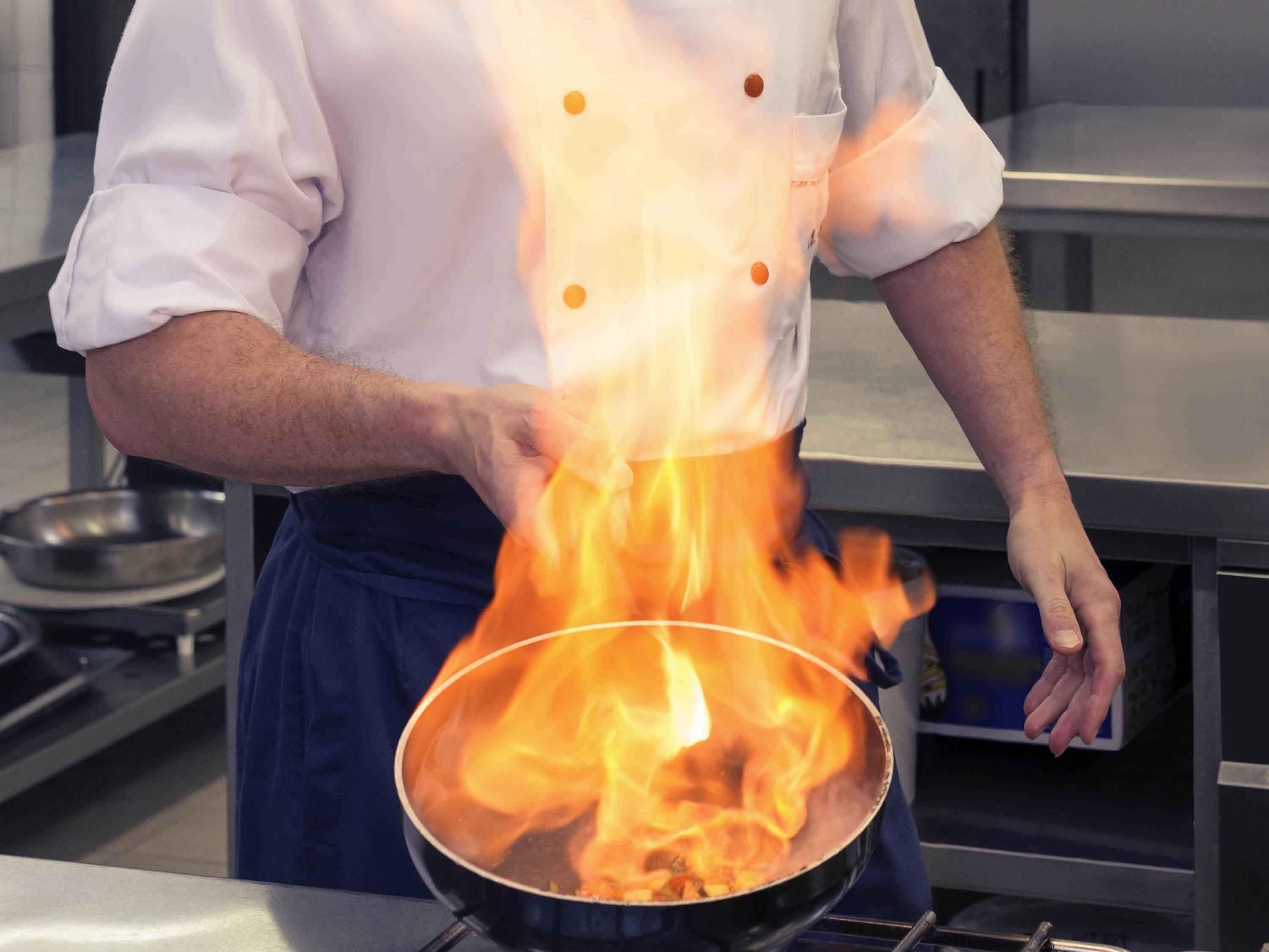 A chef cooking with a pan on a stove.