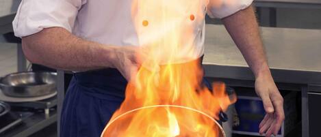 A chef cooking with a pan on a stove.