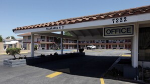 A motel with a covered parking area, a sign indicating clearance of 6'3", and an office building with the number 1222.
