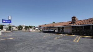 A parking lot with a building that has a tiled roof and a stone facade. There is a sign indicating the building is a Best Value Inn.