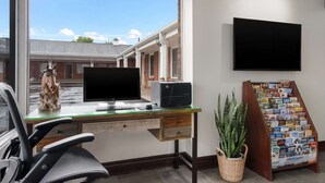 A home office with a desk, computer, and a large window overlooking a street.