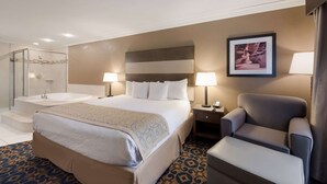 A hotel room with a large bed, a shower, a chair, and a nightstand with a lamp.