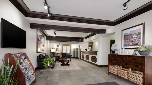 A spacious living area with a fireplace, a coffee table, and a sofa. There is a wooden cabinet with baskets and a flat-screen TV mounted on the wall.