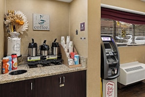 A coffee station with multiple coffee makers, a water dispenser, and a Red Roof Inn sign.
