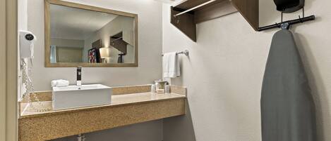 A modern bathroom with a sink, mirror, towel rack, and a hairdryer.