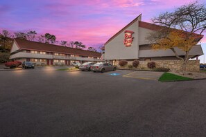 A Red Roof Inn with a parking lot and a building with a sloped roof.