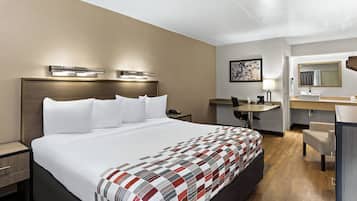 A hotel room with a large bed, bedside tables, a desk, and a bathroom with a mirror and sink.