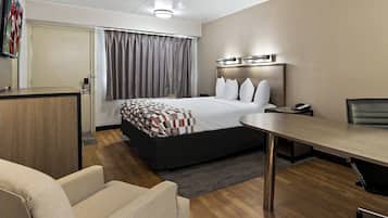 Una moderna camera d'albergo con un grande letto, una scrivania, una sedia e una TV a parete.
