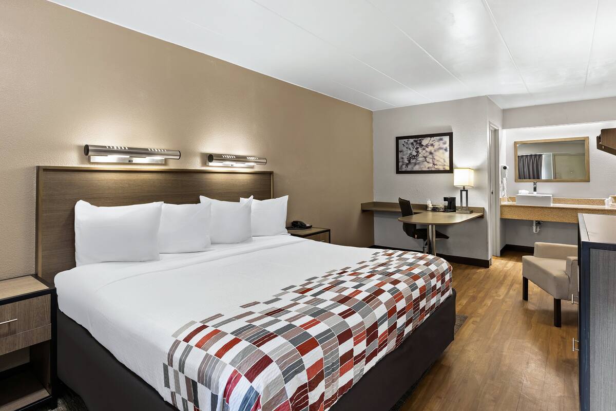 A hotel room with a large bed, bedside tables, a desk, and a chair.