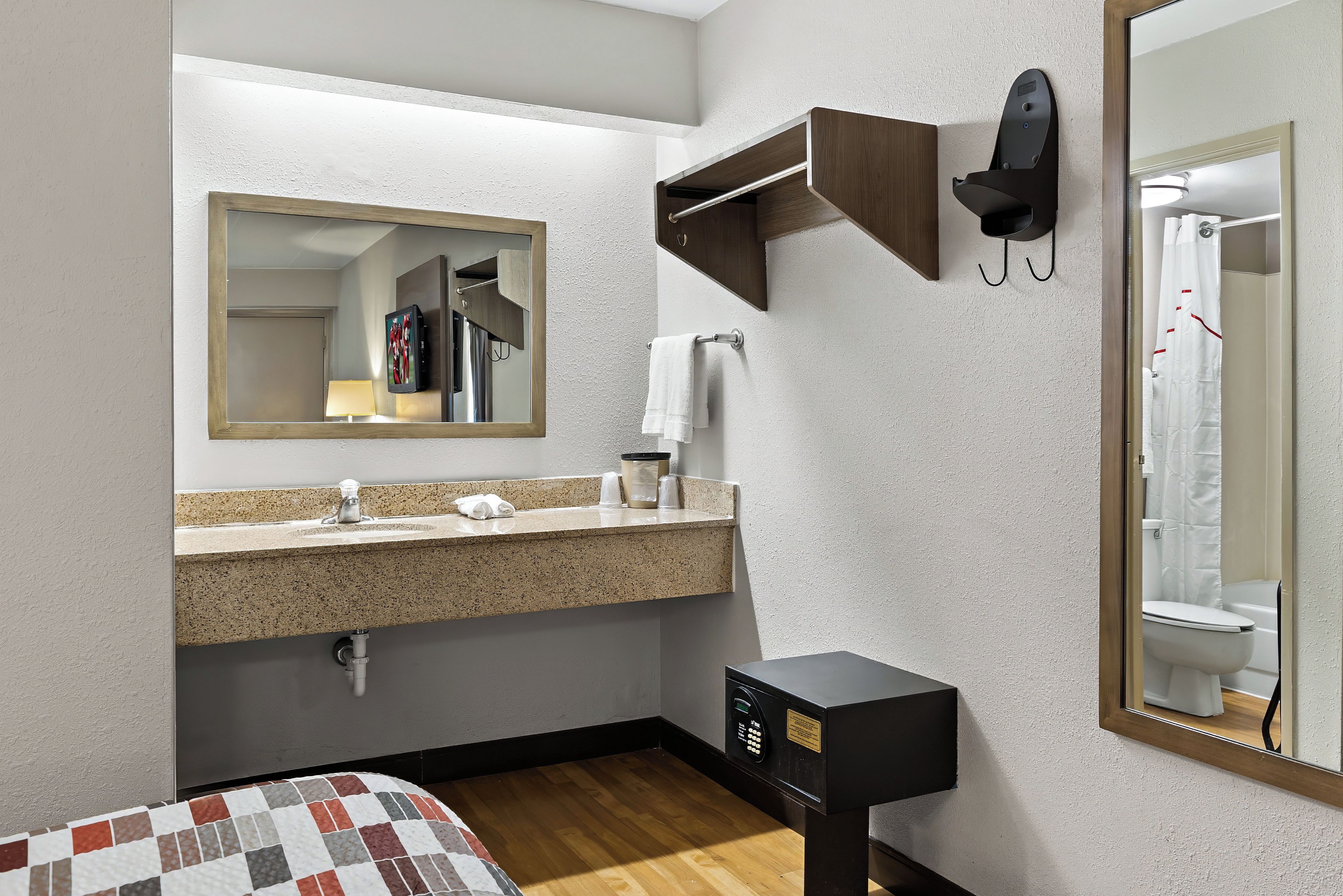 A hotel bathroom with a sink, mirror, towel rack, and a toilet.