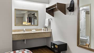 A hotel bathroom with a sink, mirror, towel rack, and a toilet.