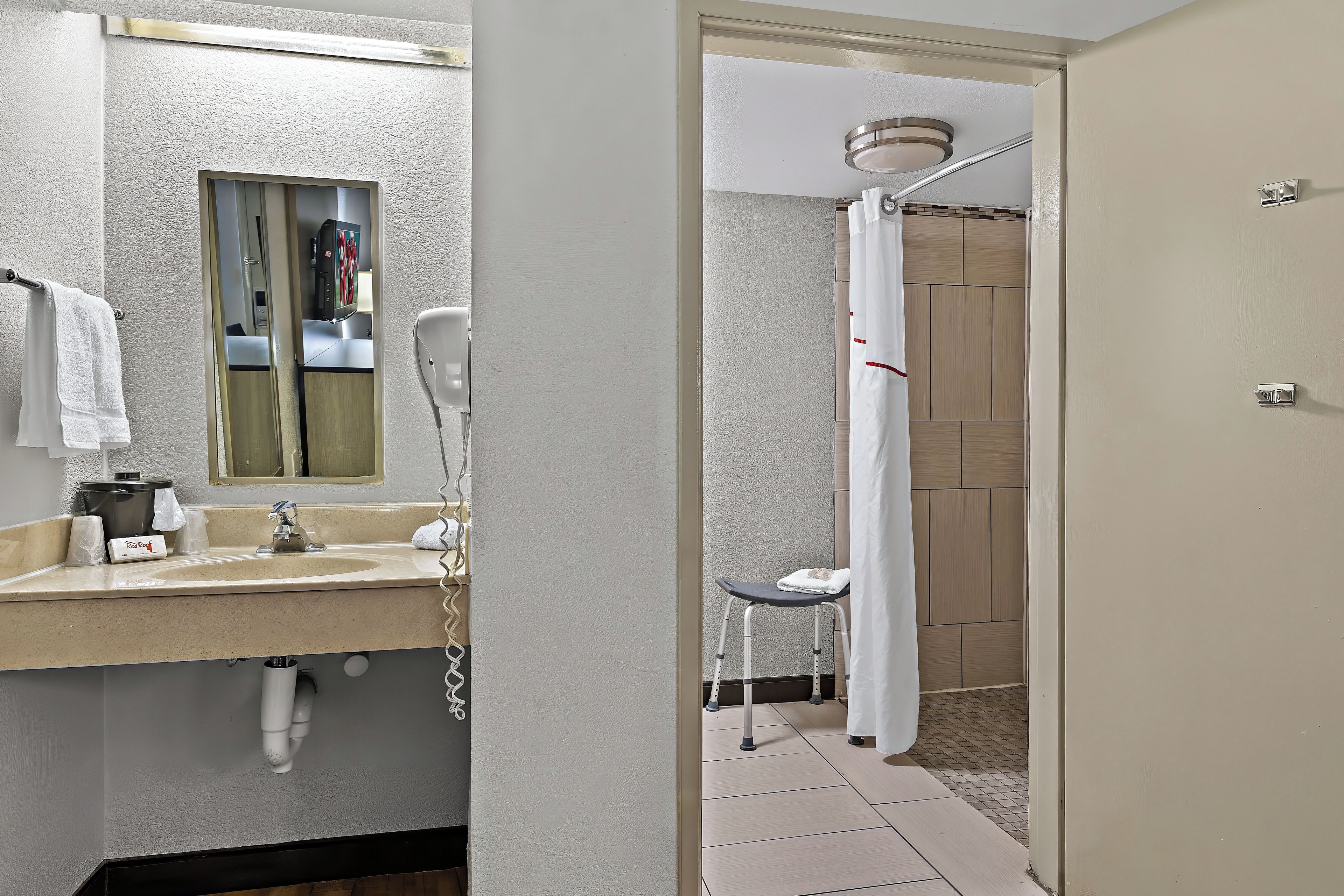 Un baño con lavamanos, espejo, toallero y una zona de ducha con cortina.
