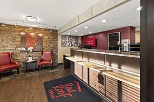 A reception area with a Red Roof sign, a reception desk, and a seating area with chairs.