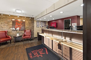 A reception area with a Red Roof sign, a reception desk, and a seating area with chairs.