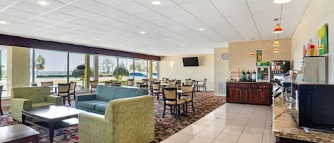 Vestíbulo de hotel con zona de estar, cocina y un amplio ventanal con vistas al exterior.
