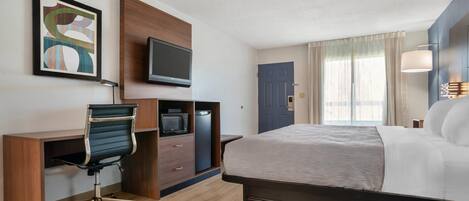 A hotel room with a bed, desk, chair, television, and artwork.