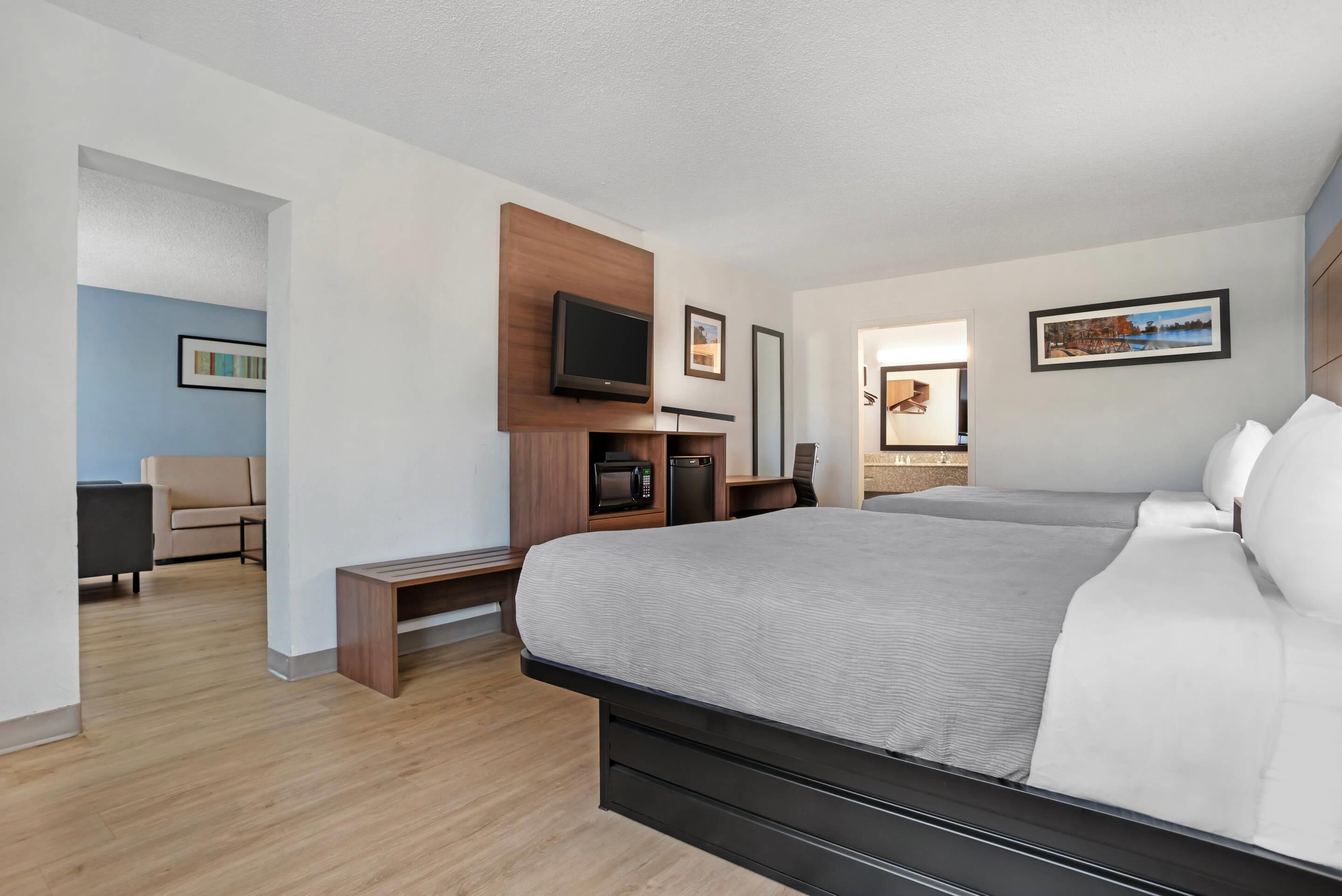 Habitación de hotel moderna con una cama grande, un televisor de pantalla plana, un escritorio con una silla y una pequeña zona de estar.