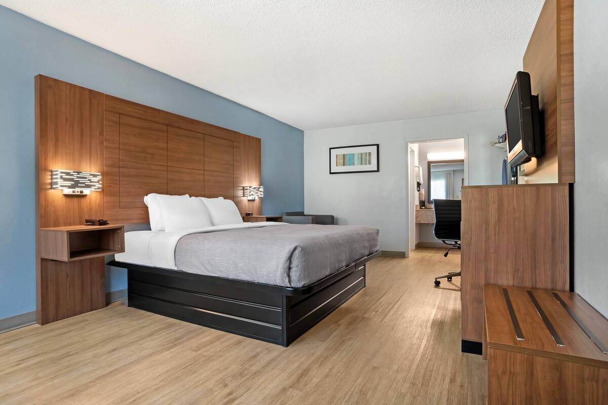 A modern bedroom with a bed, bedside tables, a TV, and a desk.