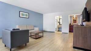 Una sala de estar moderna con un sofá gris, una mesa de centro de madera y un televisor de pantalla plana montado en la pared.