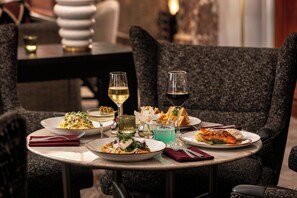 A dining table with plates of food, glasses of wine, and a vase of flowers.