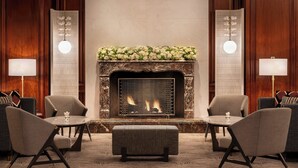 A lobby with a fireplace, two armchairs, a round table, and a bench. - The Ritz-Carlton, St. Louis (St. Louis)