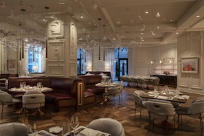 A spacious dining area with high ceilings, elegant furniture, and a modern chandelier.