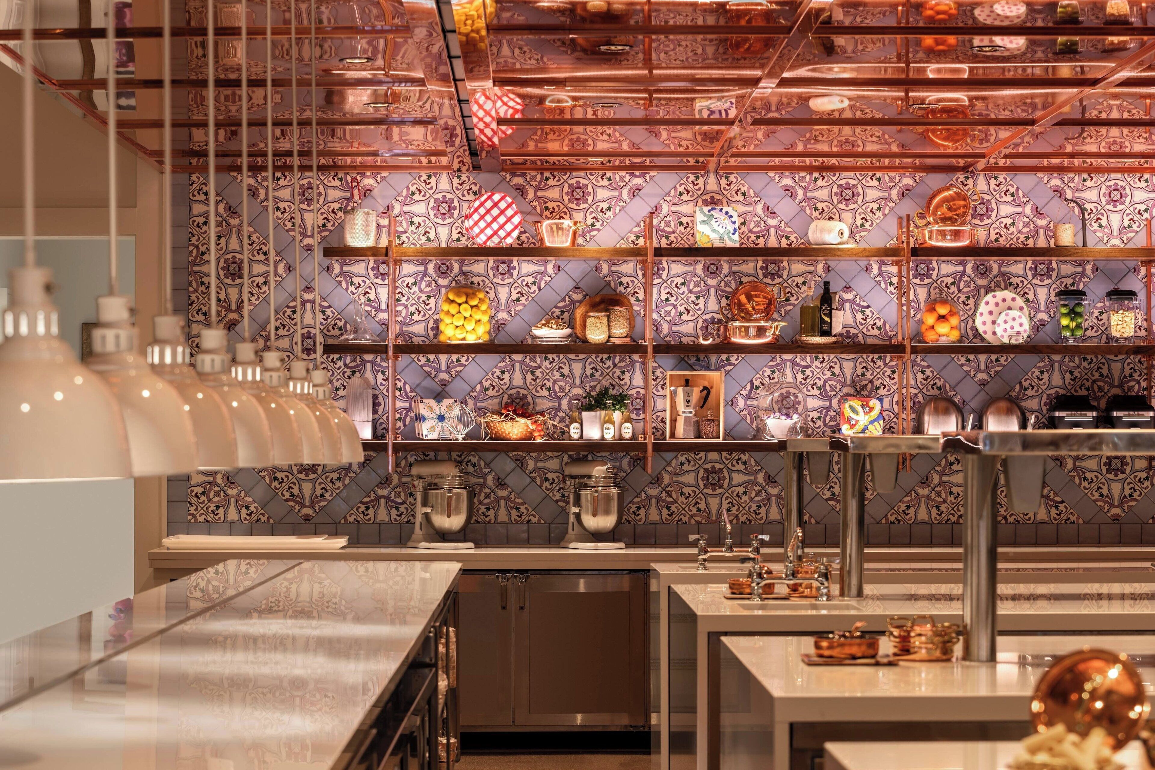 A modern kitchen with a tiled backsplash, stainless steel appliances, and a variety of kitchenware displayed on shelves.