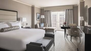 A hotel room with a large bed, a desk, a chair, and a view of the city through the window.