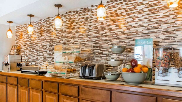 A breakfast bar with a brick-patterned backsplash, a coffee machine, a toaster, and a fruit bowl. - Quality Inn US65 & E. Battlefield Rd. Springfield (Springfield)