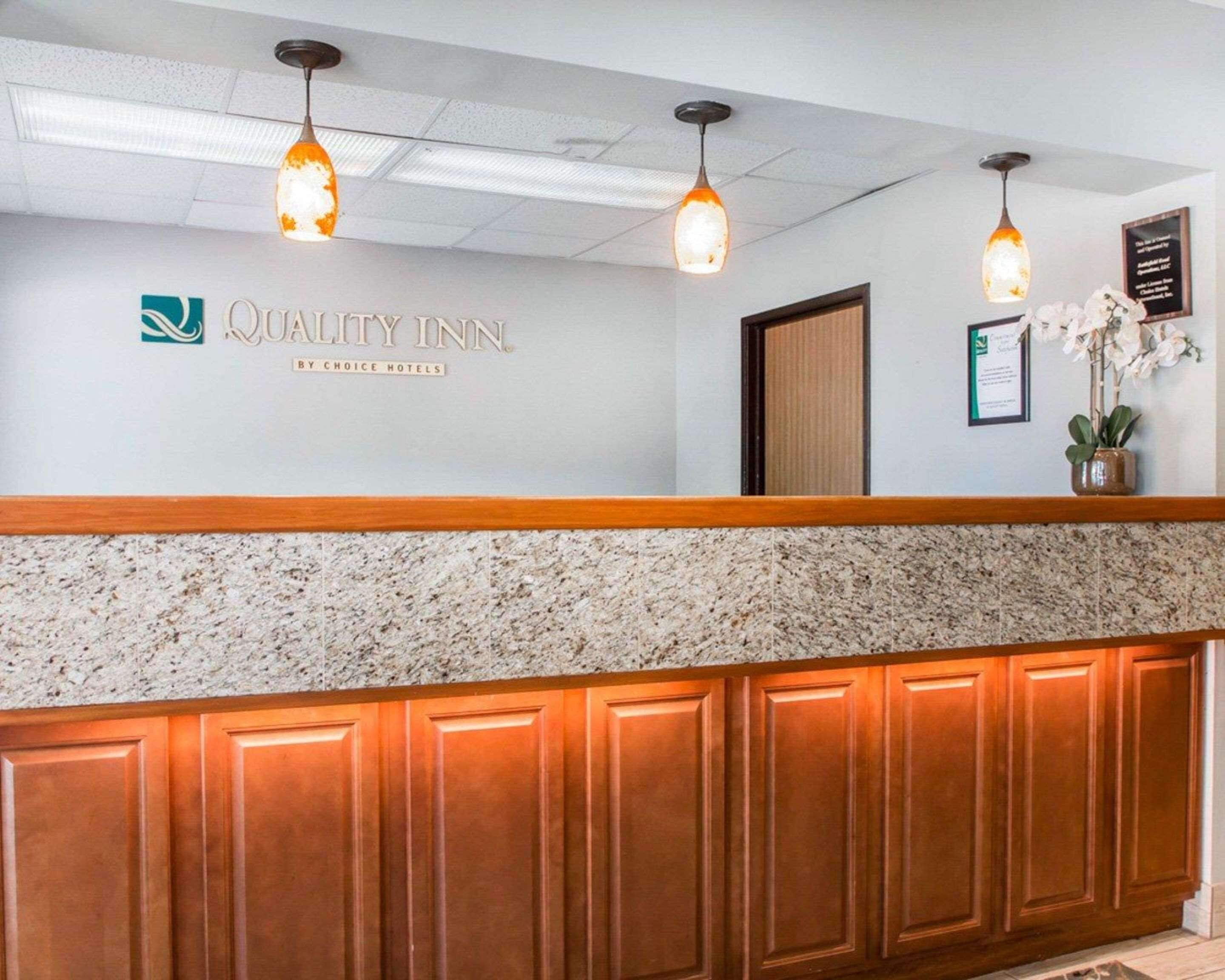 A reception area with a marble counter, wooden paneling, and two pendant lights.