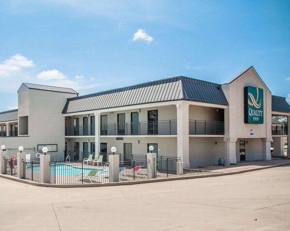 A two-story hotel with a swimming pool, a covered outdoor area, and a sign for Quality Inn.