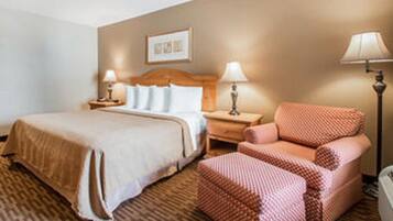 A hotel room with a bed, two bedside tables with lamps, a chair, and a framed picture on the wall.