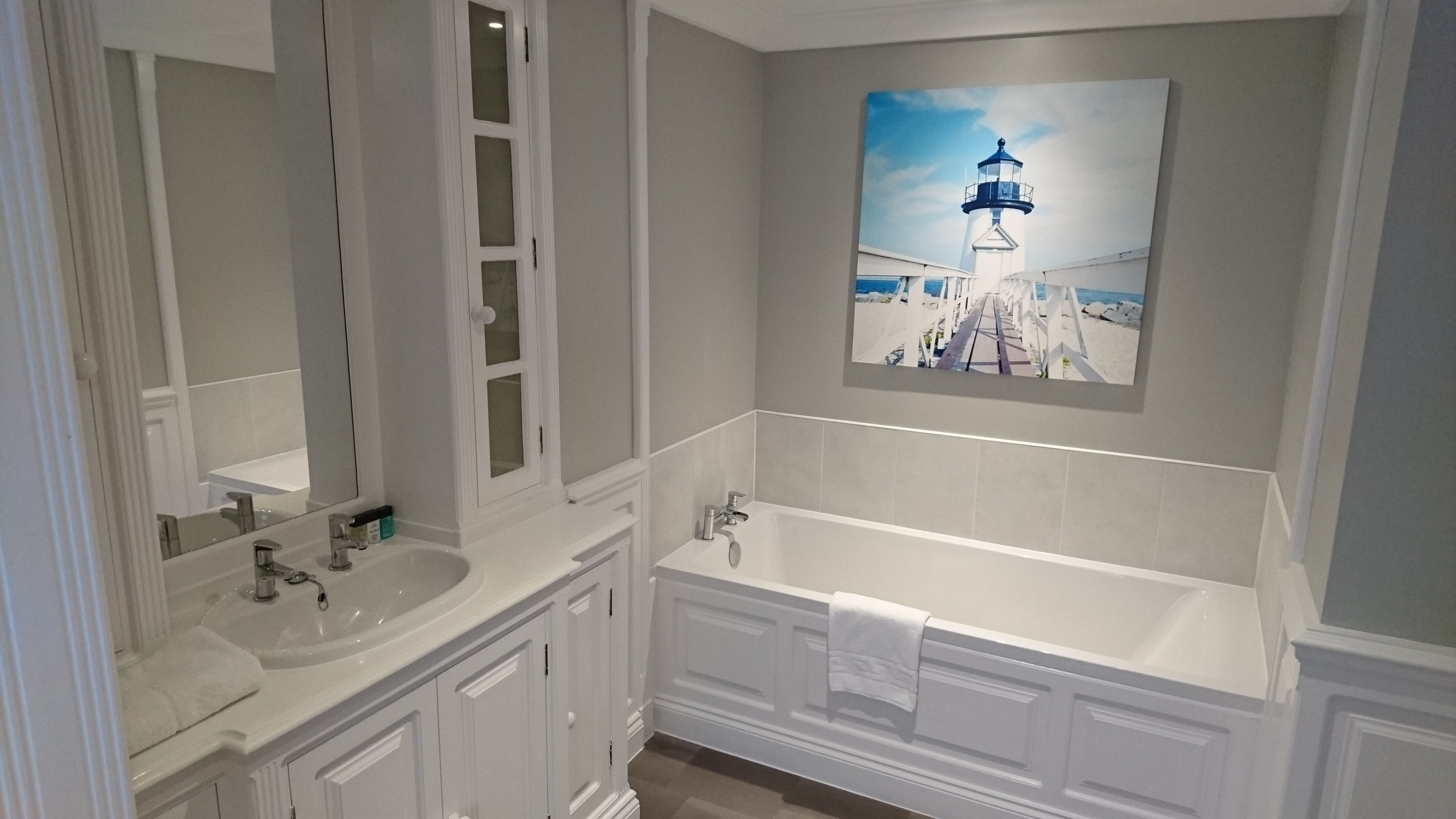 Un baño con un espejo grande, un lavabo y una bañera.