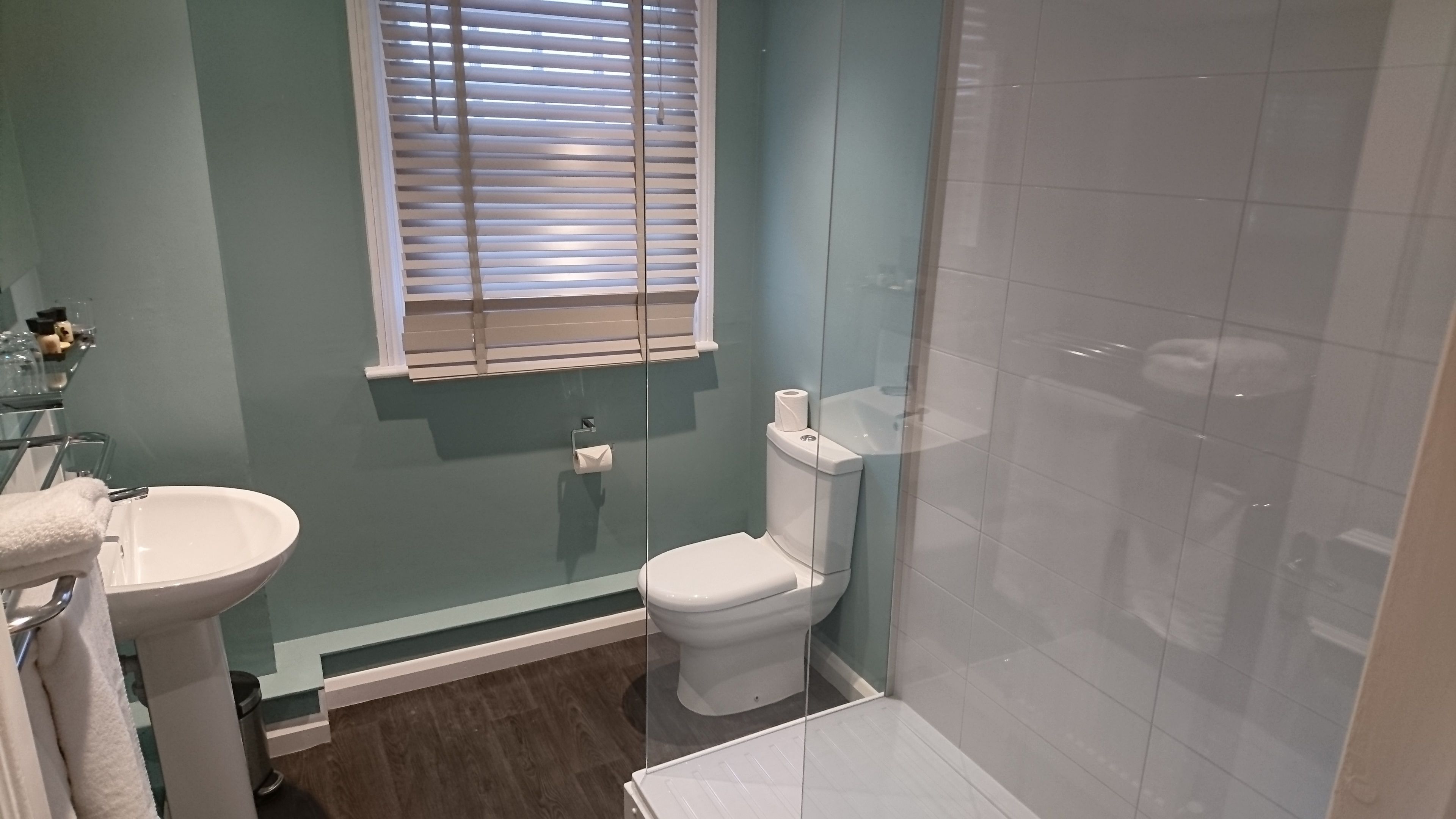 Ein Badezimmer mit Toilette, Waschbecken und einer Duschkabine aus Glas.