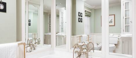 A bathroom with a large mirror, a bathtub, a toilet, and a sink.