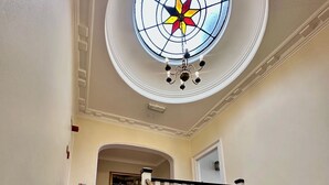 Una escalera con peldaños cubiertos de alfombra roja y barandillas blancas, que conduce a una habitación con una puerta blanca y un extintor en la pared.