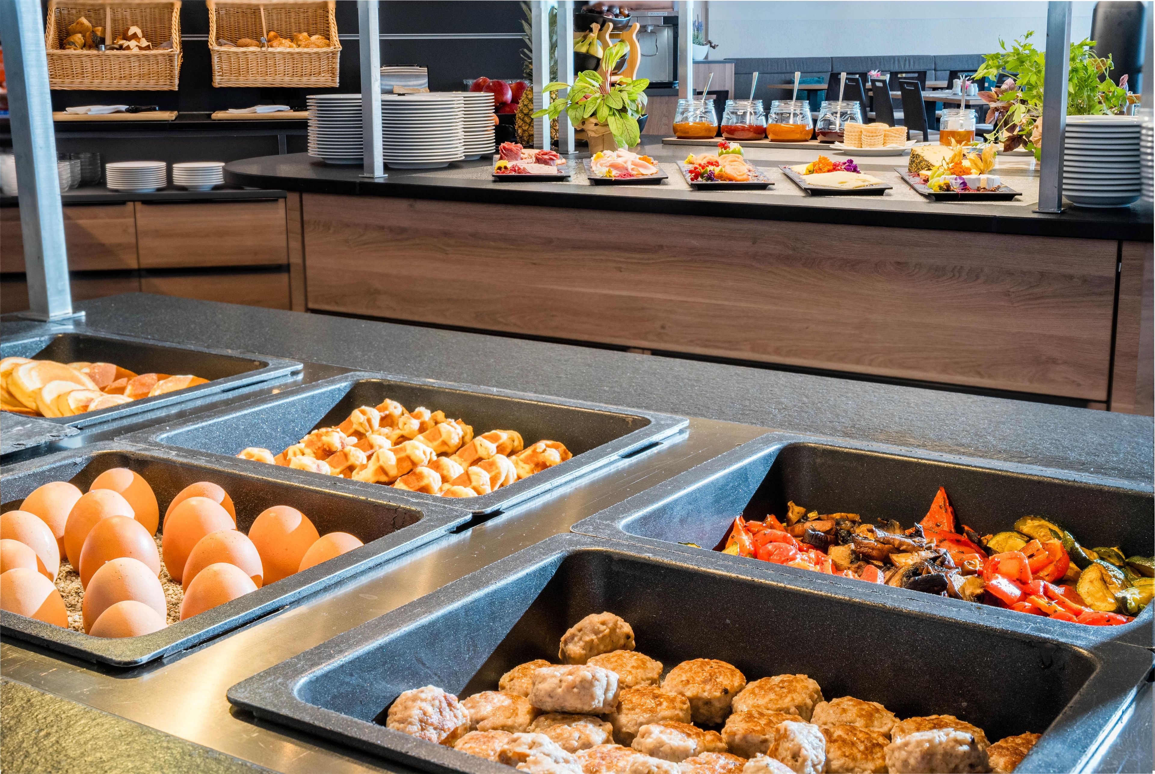 Un bufé con diversas opciones de comida, incluyendo huevos, verduras y carne.