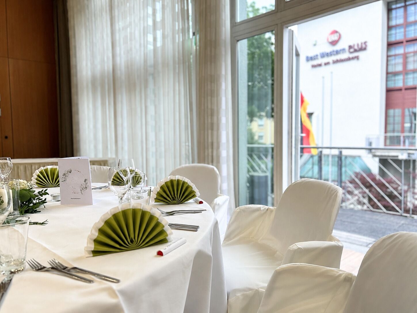 A table set for dining with a view of a building with a sign that reads 'Best Western.'