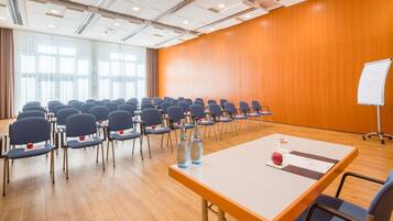 A conference room with rows of chairs, a whiteboard, and a table with water bottles and an apple.